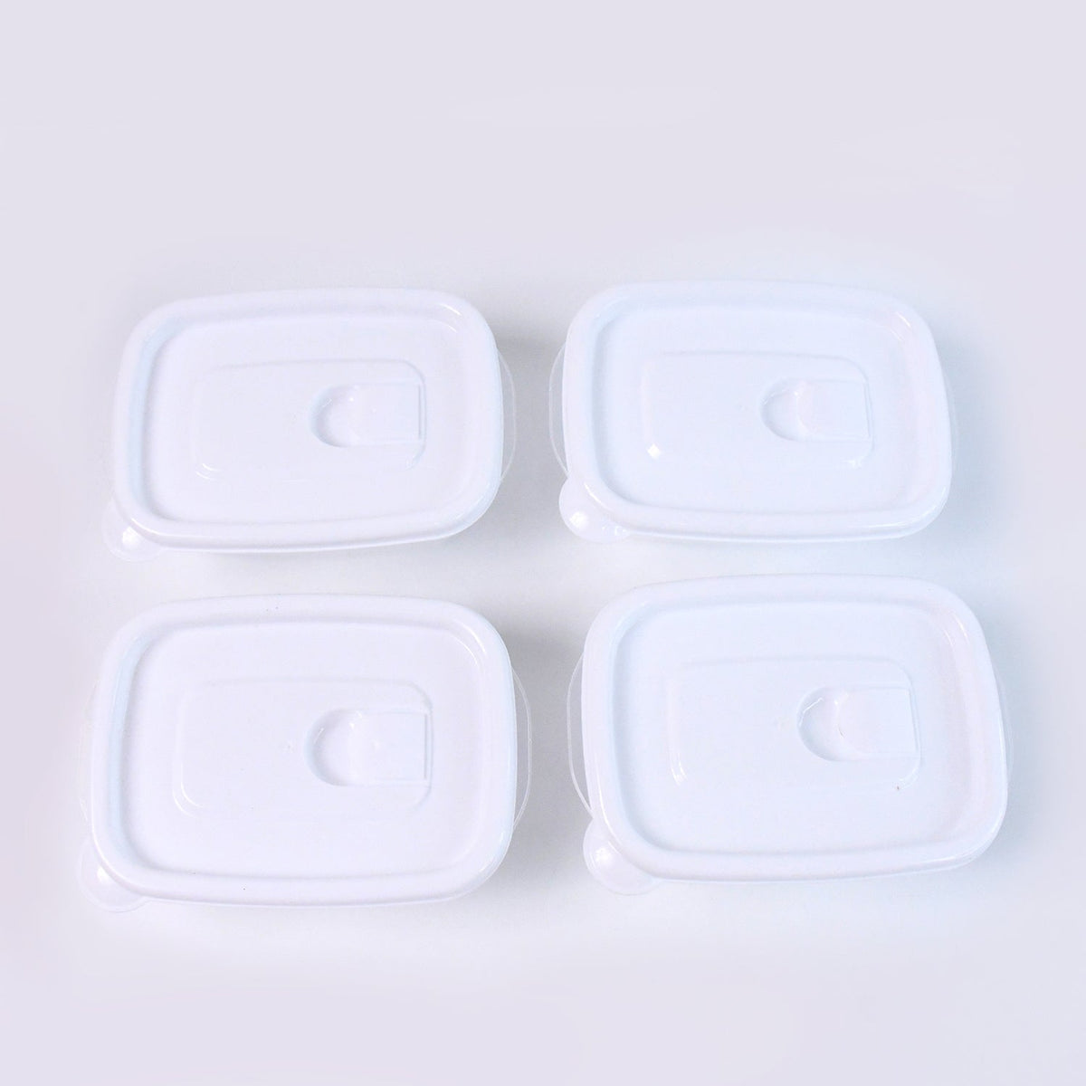 Top-down view of four clear plastic food containers with white lids neatly arranged on a plain white background.