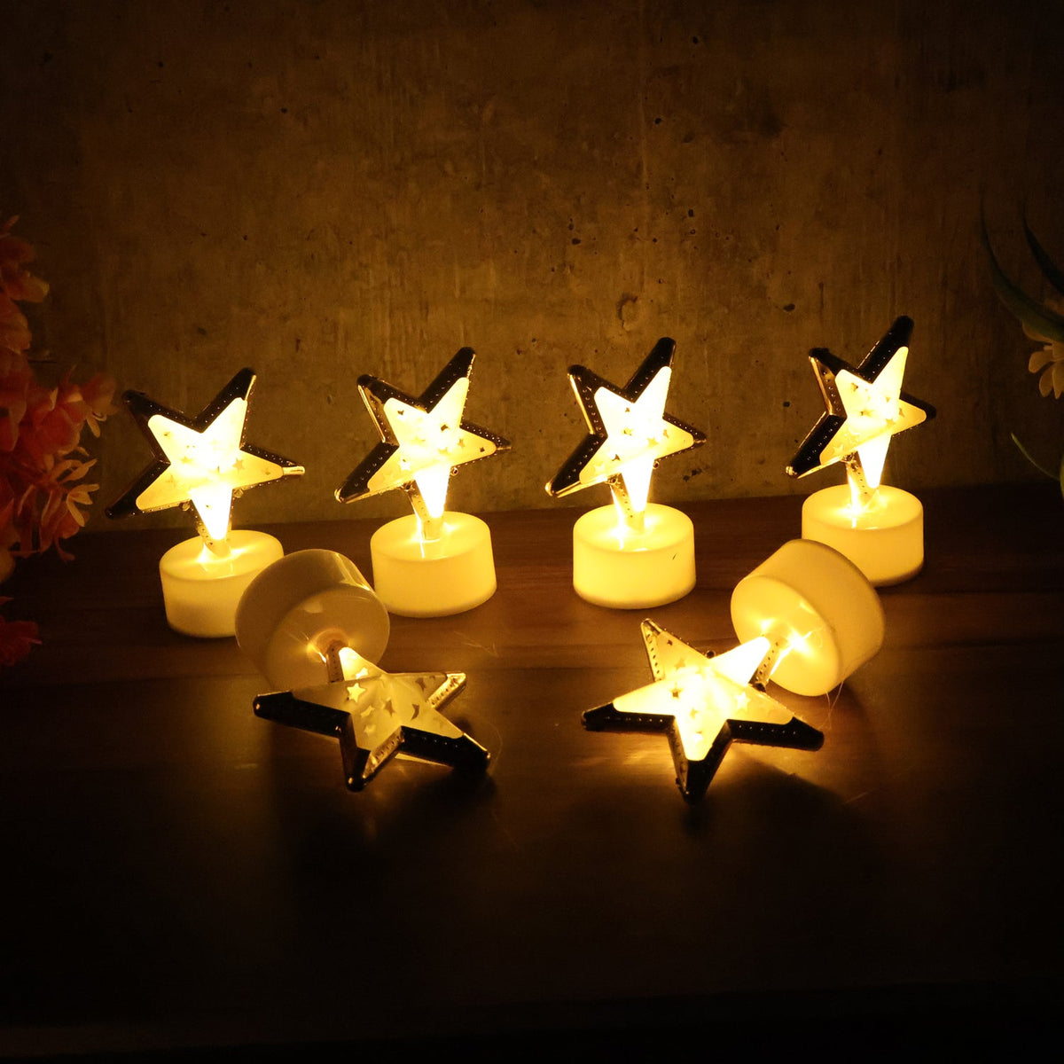 Seven glowing star-shaped LED candles, some upright and some lying down, on a dark wooden surface.