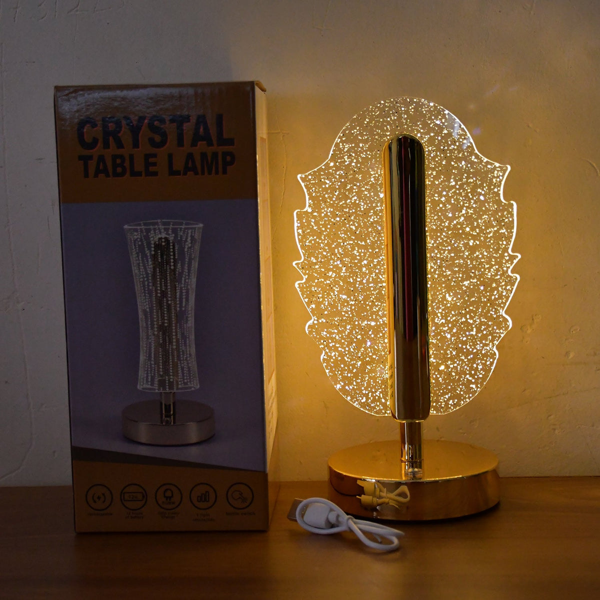 A feather-shaped crystal table lamp next to its product box, which displays a different lamp design.