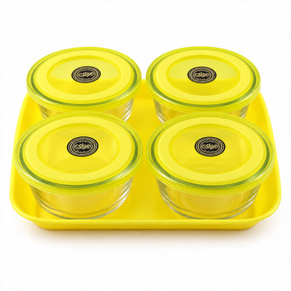 A top-down view of four clear glass bowls with yellow lids, arranged on a yellow rectangular tray.