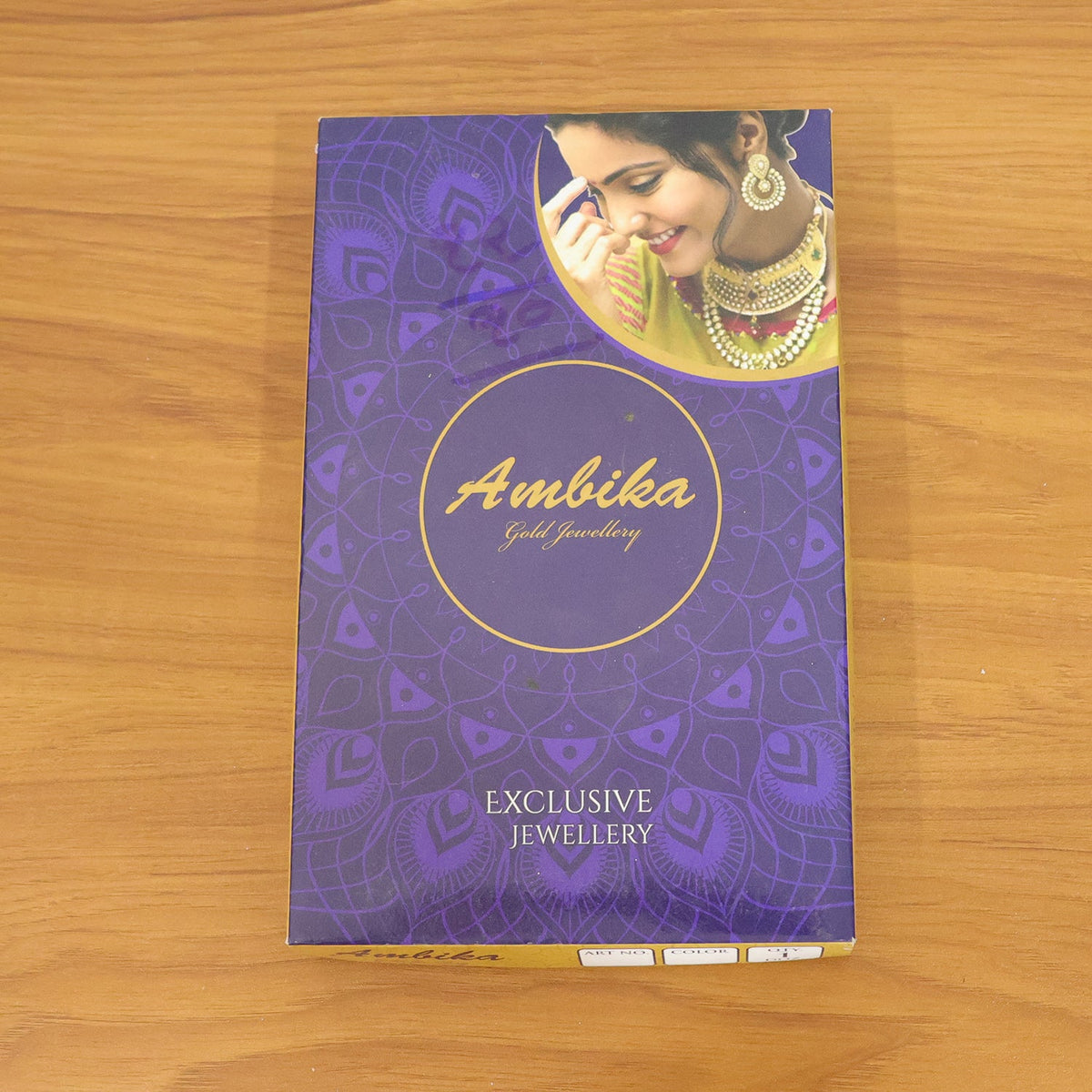 A purple and gold box for "Ambika Gold Jewellery" featuring a woman wearing traditional Indian jewelry.