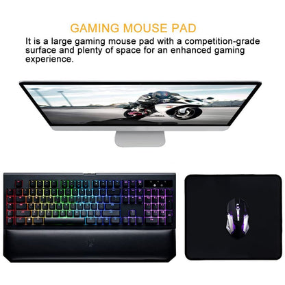A black mouse pad with a gaming mouse next to a colorful gaming keyboard and a monitor displaying a motorcycle.