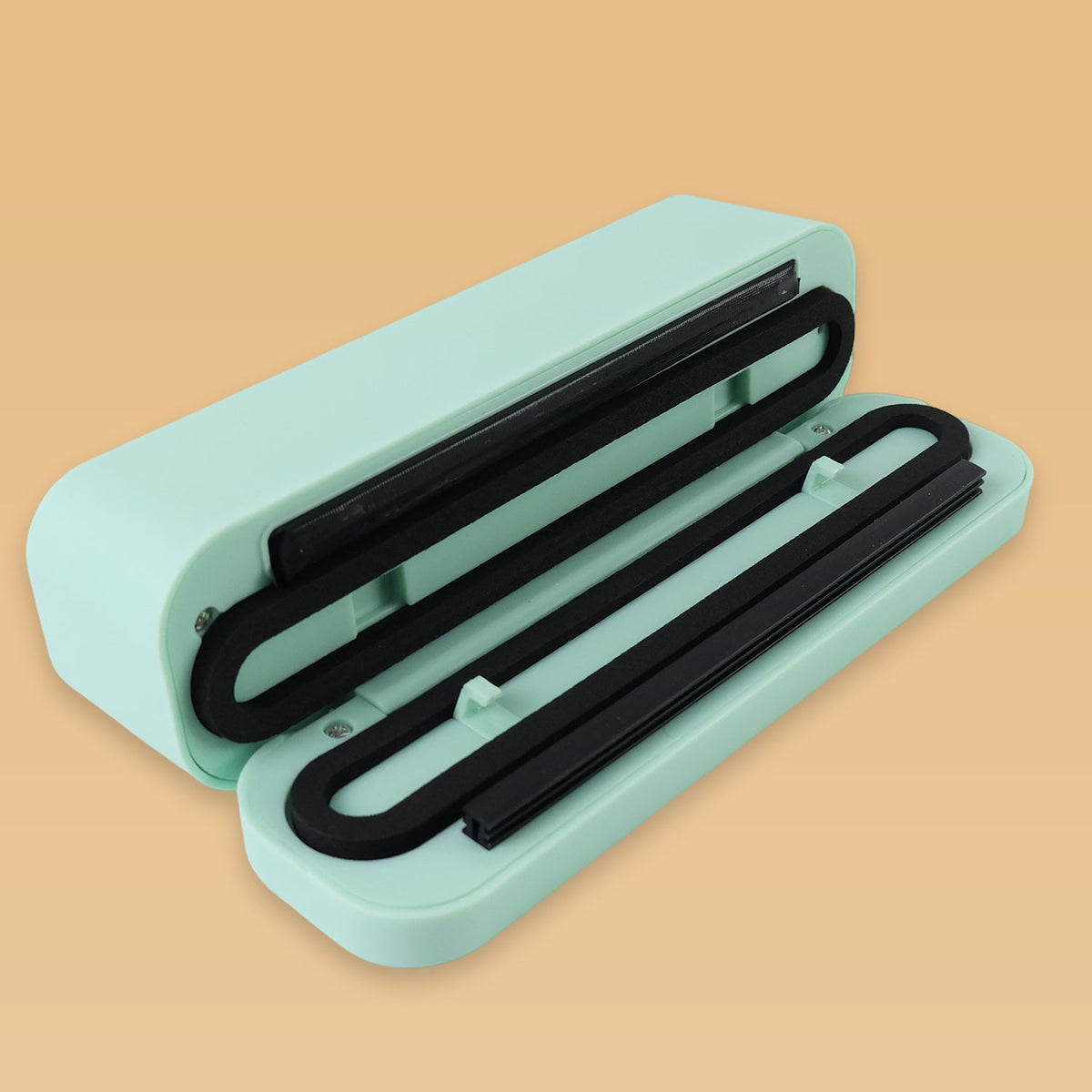 The mint green handheld vacuum sealer opened up, revealing black sealing strips inside its light green casing.