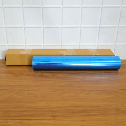 A rolled blue mirror film and a brown cardboard box on a wooden surface.