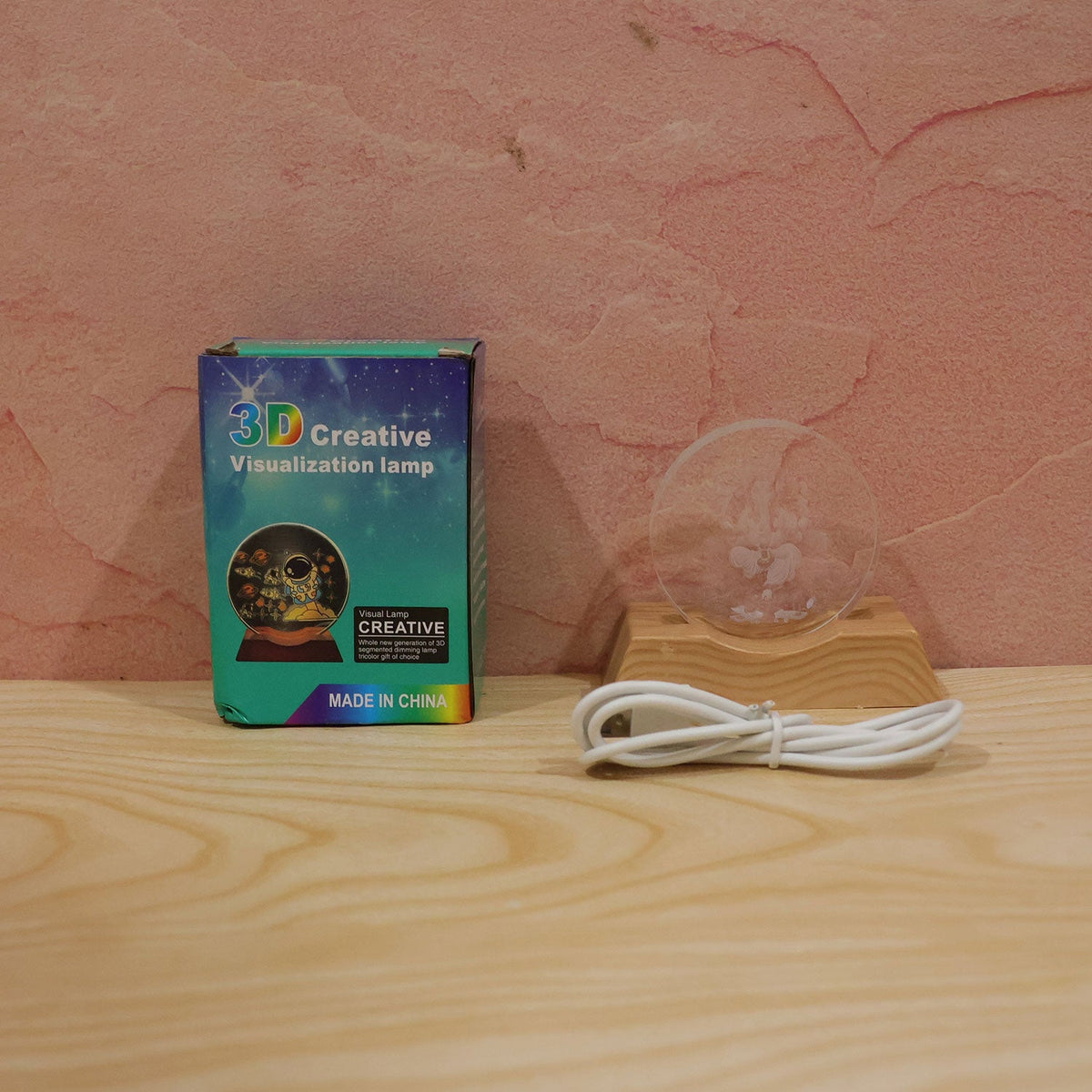 Ganesha LED lamp components including the engraved plate, wooden base, USB cable, and product box on a wooden surface.