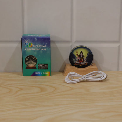 Shiva LED lamp, USB cable, and its blue and green packaging box displayed on a light wooden surface.