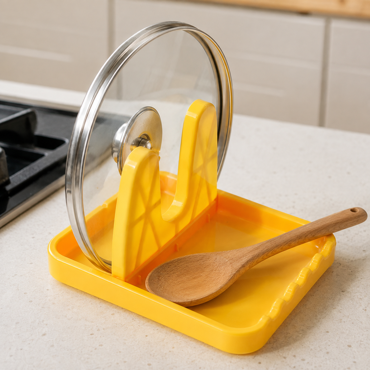 A yellow plastic lid and spoon rest holding a glass pot lid and a wooden spoon on a kitchen counter.