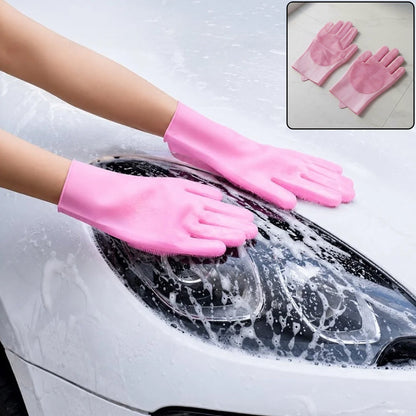 A person wearing pink silicone gloves with scrubbers on the palms and fingers, washing a white car with soap suds.