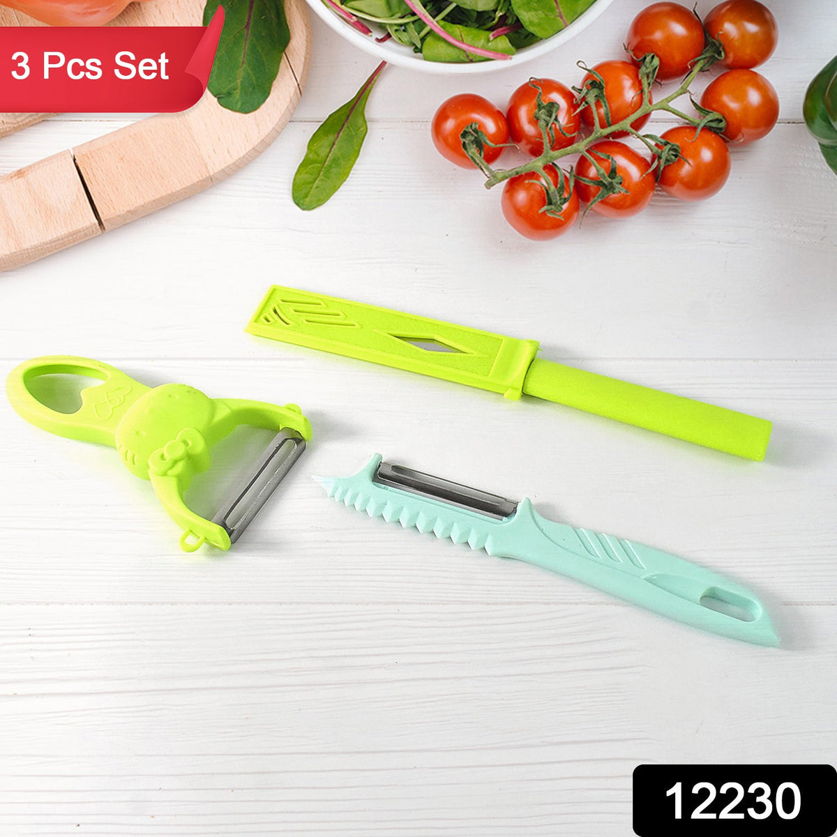 A green peeler, a teal peeler, and a green knife on a white wooden surface with tomatoes and greens.