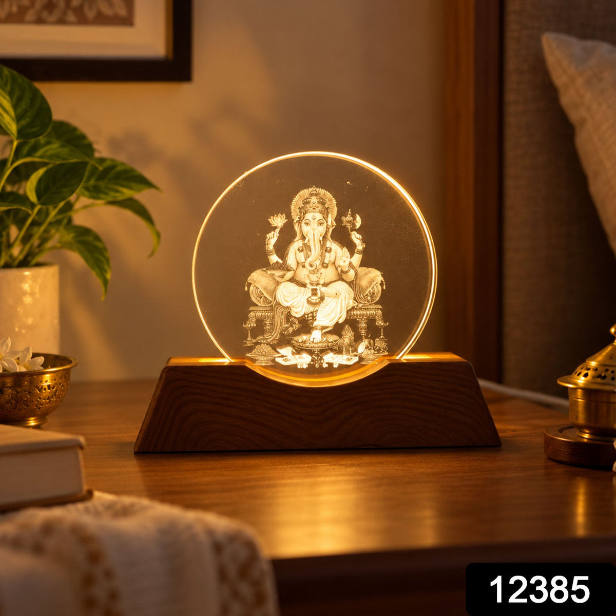 Ganesha LED lamp with a wooden base, emitting a warm glow, placed on a dark wooden table beside a book and plant.
