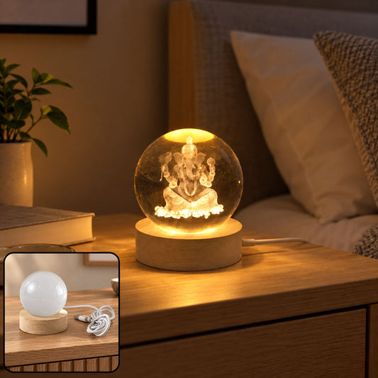 A glowing crystal ball with a Ganesha engraving sits on a wooden base on a bedside table.