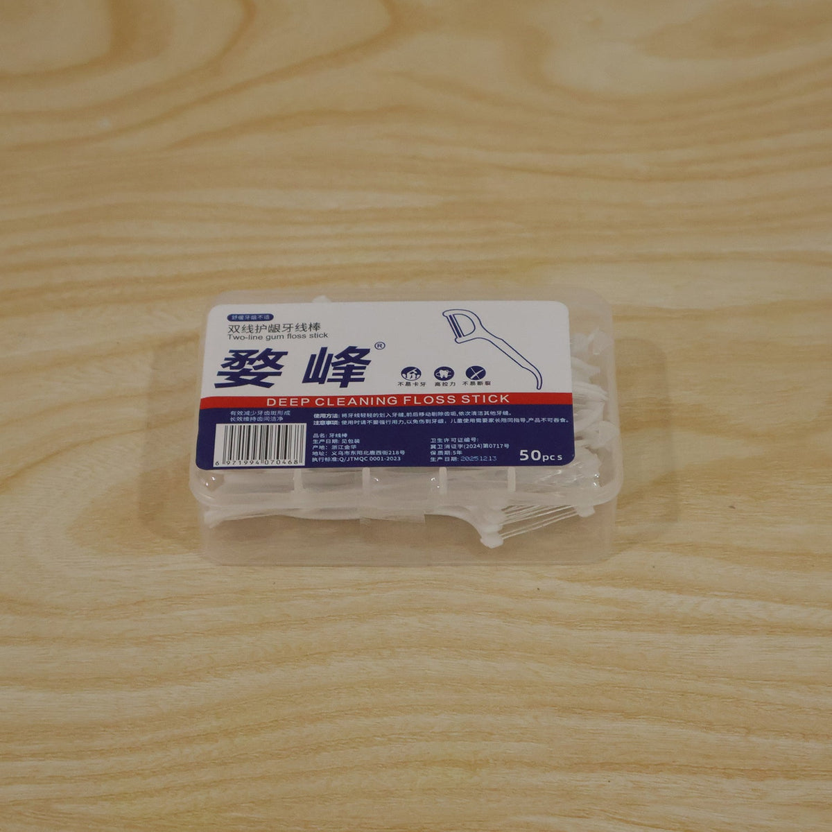 A clear plastic storage box filled with white dental floss picks sits on a light wooden surface.