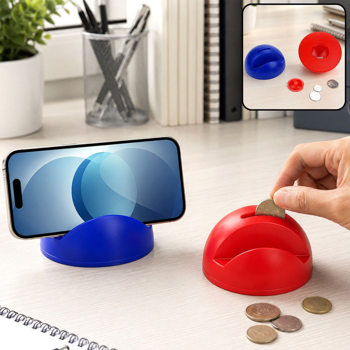 A blue phone holder with a phone and a red piggy bank with coins being inserted on a white desk.