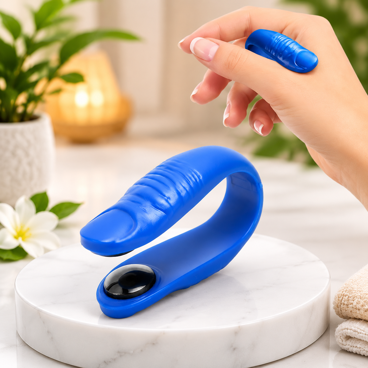 A blue acupressure hand clip with a black magnet sits on a white marble surface, while another is held by a hand.