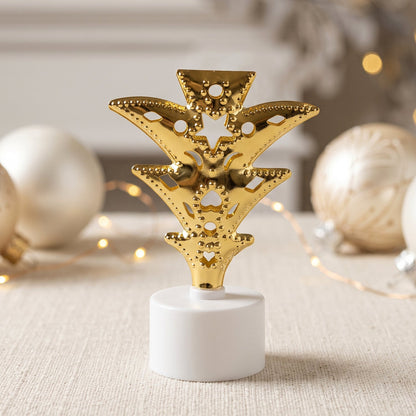 A single golden Christmas tree LED tealight glows brightly against a blurred background of white ornaments.