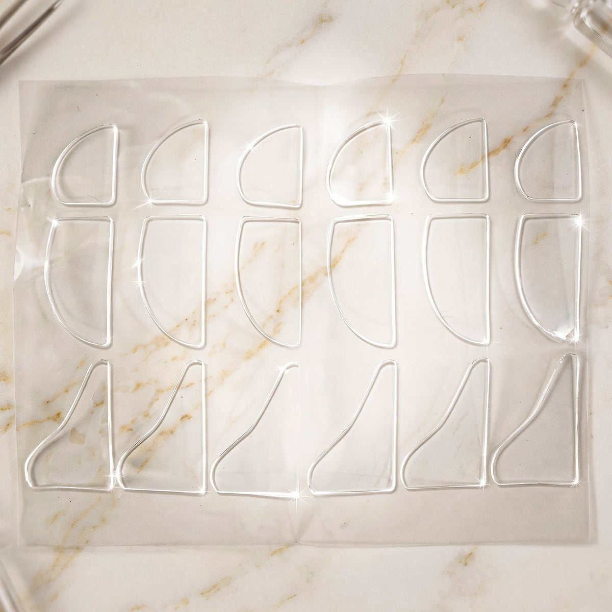 A sheet of clear, adhesive corner protectors, some rounded and some L-shaped, on a marble-patterned surface.