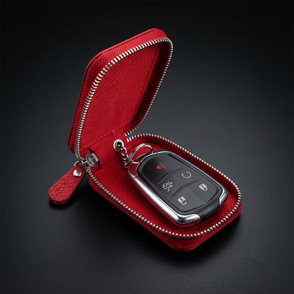 Open red zippered leather car key case with a black car key attached to the internal chain, on a dark background.