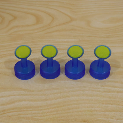 Four identical blue and green plastic bottle cap sprinklers are lined up neatly on a light wooden surface.