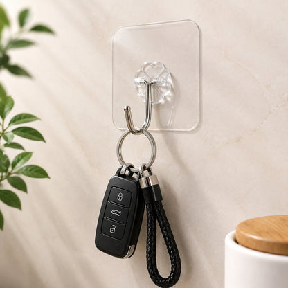 A GlimmerHome clear adhesive hook with a silver stainless steel hook holds a black car key fob and a braided leather