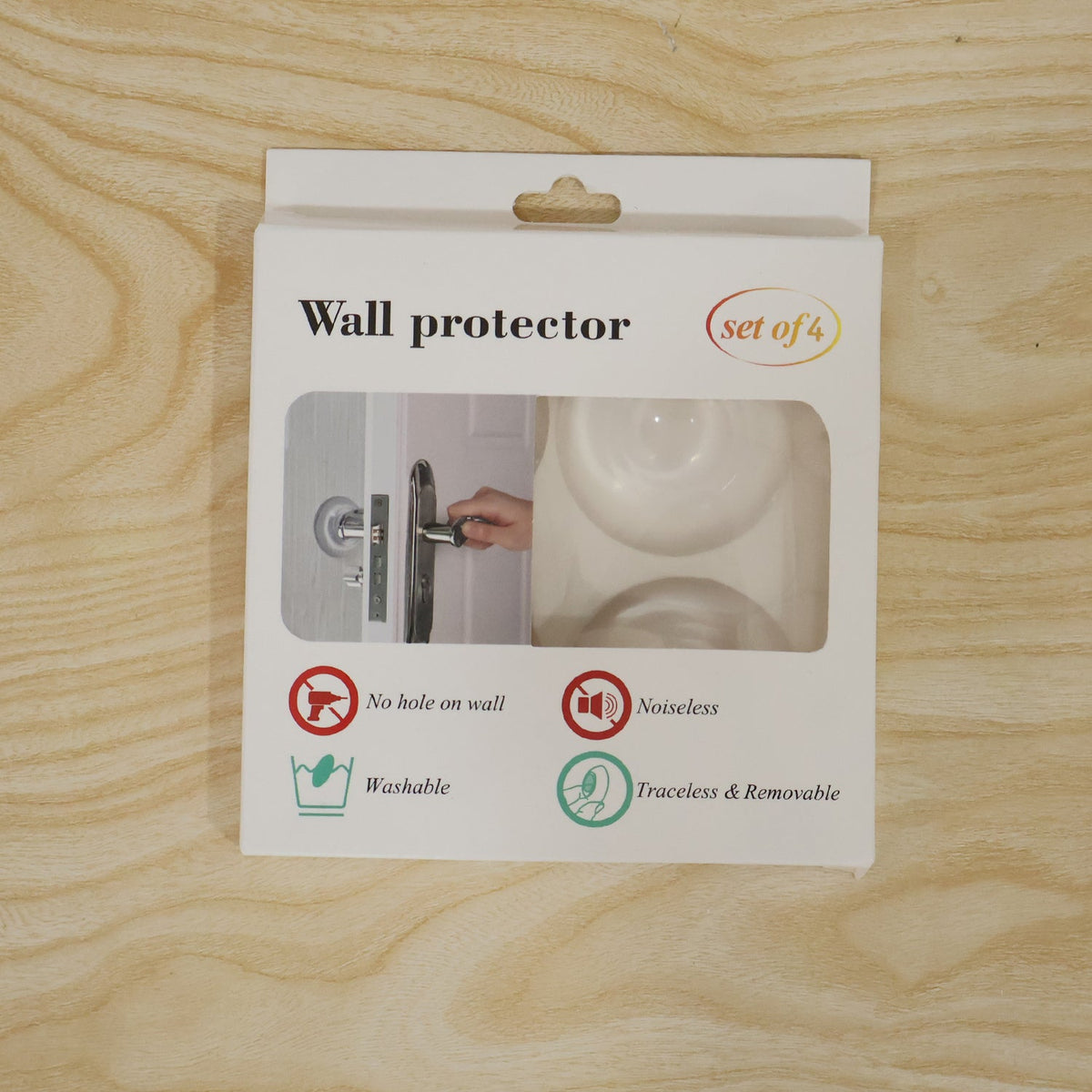 A white product box for wall protectors, displaying a clear window and descriptive icons, rests on a light wooden surface.