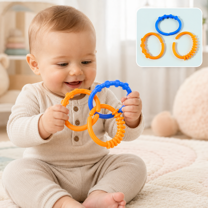 A smiling baby sits on a rug, holding and playing with three interconnected orange and blue learning links.