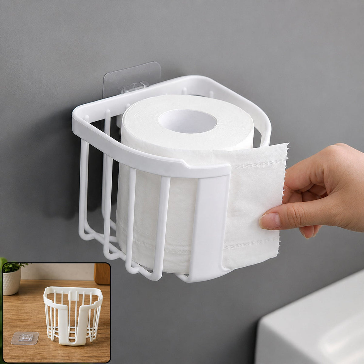 A white plastic toilet paper holder is mounted on a gray wall, holding a roll of toilet paper as a hand tears a sheet.
