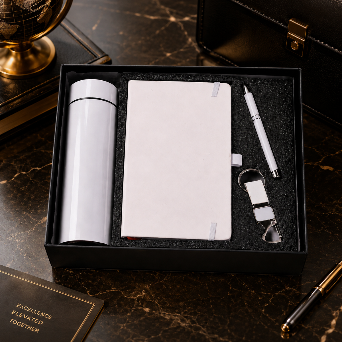 White thermal bottle, notebook, pen, and keychain in a black gift box on a dark marble surface.