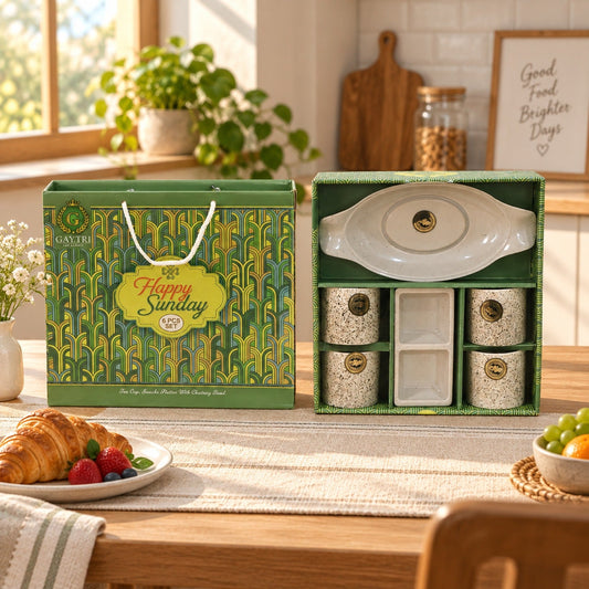 A green and gold gift box with an open box revealing a white ceramic snack and tea set.
