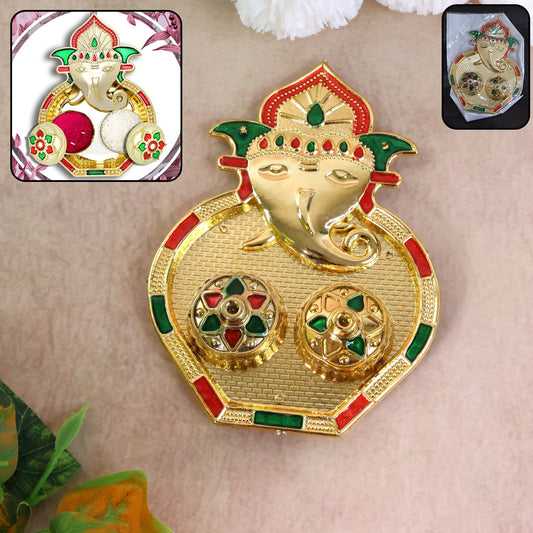 A golden Ganesh pooja thali with two small round containers, accented with red and green enamel details.