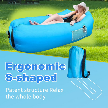 A woman lounges on an ergonomic S-shaped blue inflatable lounger with a carry bag nearby, on a blue and green background.