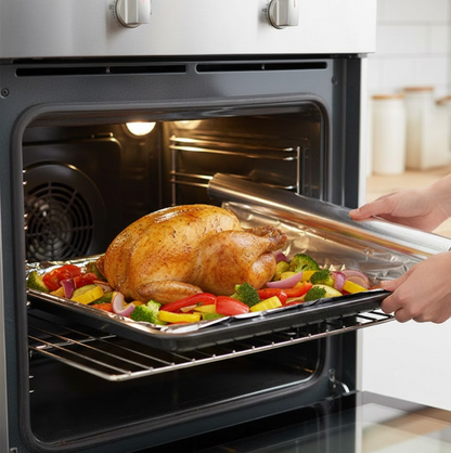 Hands placing a baking sheet with a roasted chicken and vegetables, covered with foil, into an oven.