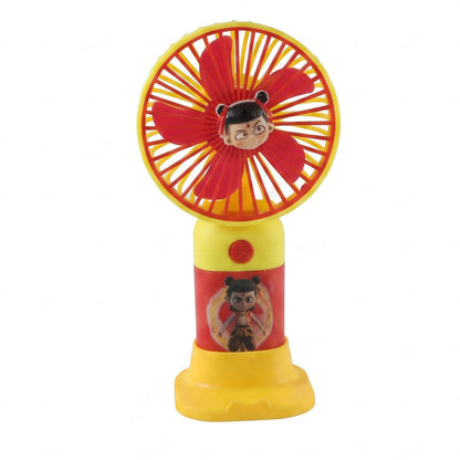 A red and yellow mini fan with a cartoon character face and stand, on a white background.