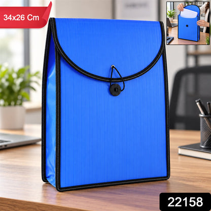 A blue plastic folder with a black elastic closure, standing on a wooden desk, with a laptop and plant in the background.