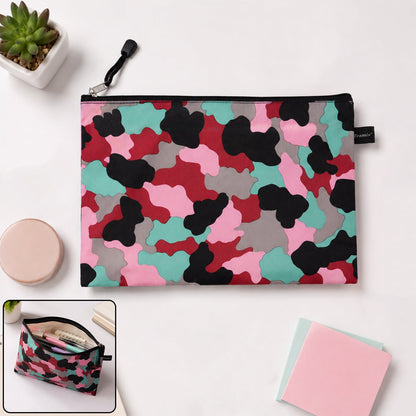 A flat, closed pouch with a pink, red, black, grey, and teal camouflage pattern, lying on a white surface next to a small