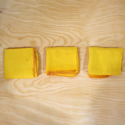 Actual photograph of three folded yellow cotton dusters