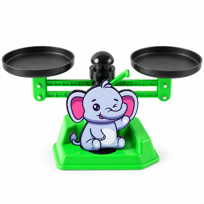 A green plastic elephant-themed math balance scale with two black weighing pans on a white background.
