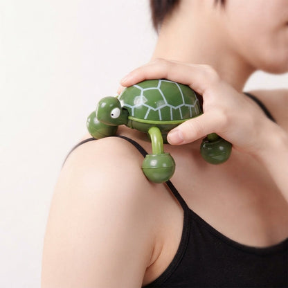 A person's hand manipulates a green turtle massager over their shoulder, highlighting the rolling feet in action.
