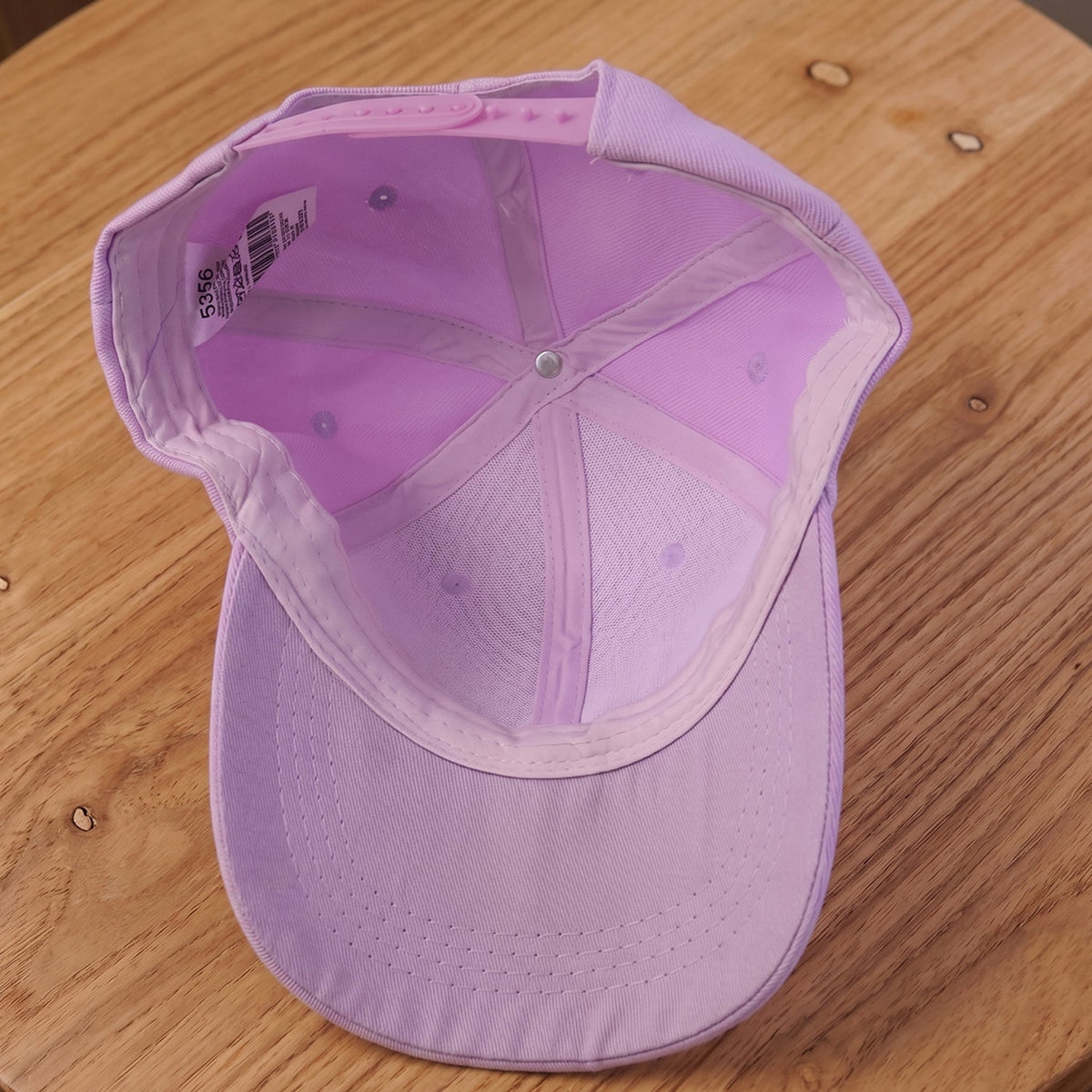 Inside view of a lavender baseball cap showing the internal stitching, sweatband, and adjustable strap.