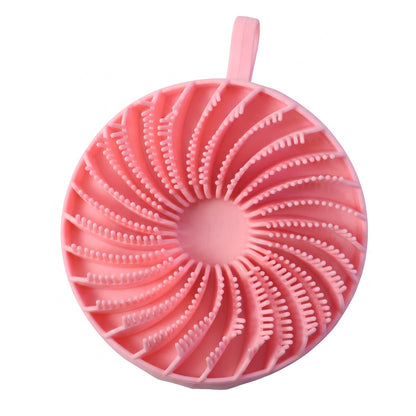 A pink silicone body scrubber with a spiral pattern of bristles and a hanging loop is shown on a white background.
