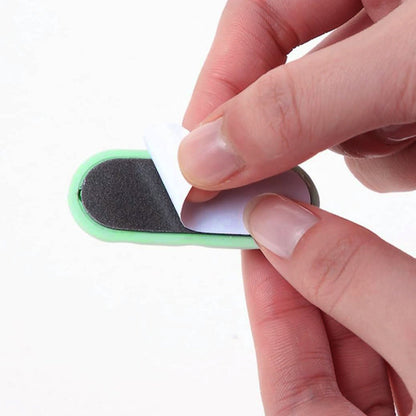 Hands peel the adhesive backing off a green silicone cable organizer.