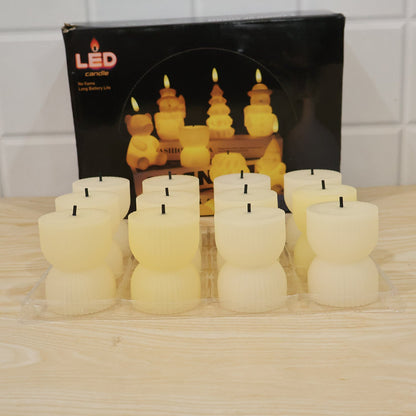 Twelve unlit, cream-colored, ribbed, hourglass-shaped LED candles are displayed in a clear plastic tray in front of their