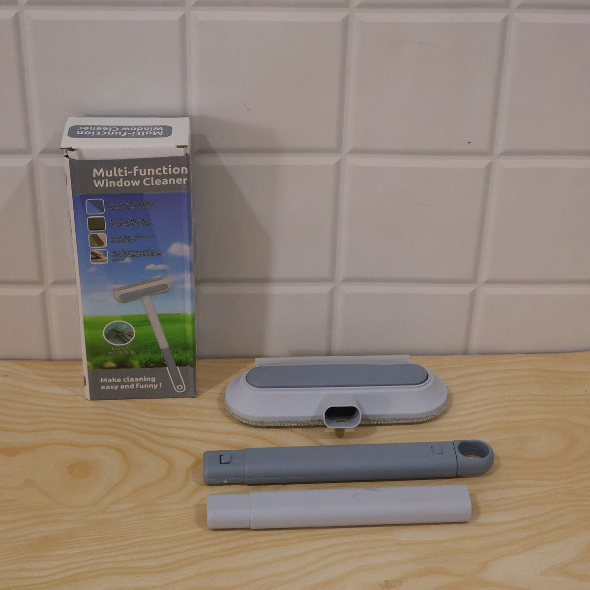 The cleaning tool components, including the head, handle parts, and packaging, are displayed on a wooden surface.