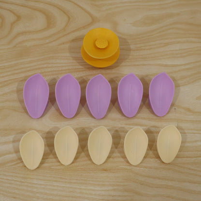 Ten individual petals, five purple and five yellow, arranged in two rows with a yellow flower center on a light wooden