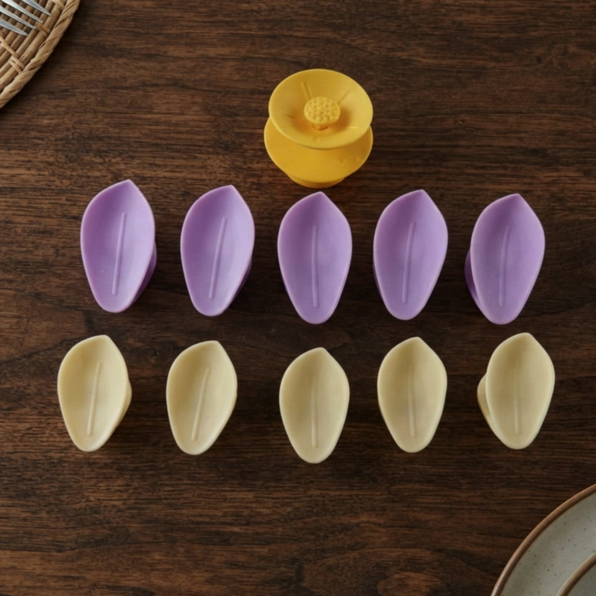Ten individual petals, five purple and five yellow, arranged in two rows with a yellow flower center on a wooden surface.