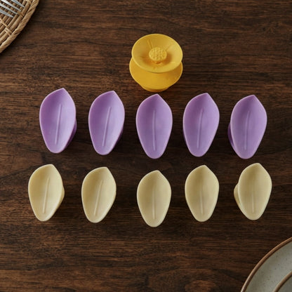 Ten individual petals, five purple and five yellow, arranged in two rows with a yellow flower center on a wooden surface.