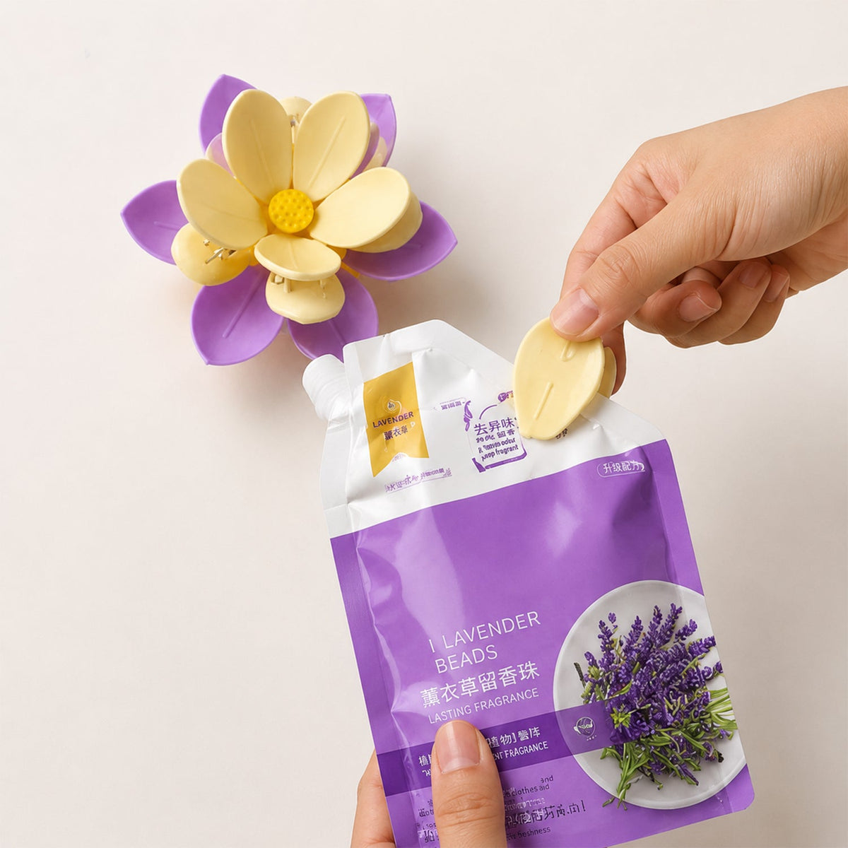 A hand inserting a yellow petal into a purple and yellow flower clip, next to a lavender bead pouch.