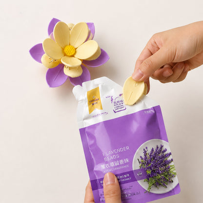 A hand inserting a yellow petal into a purple and yellow flower clip, next to a lavender bead pouch.