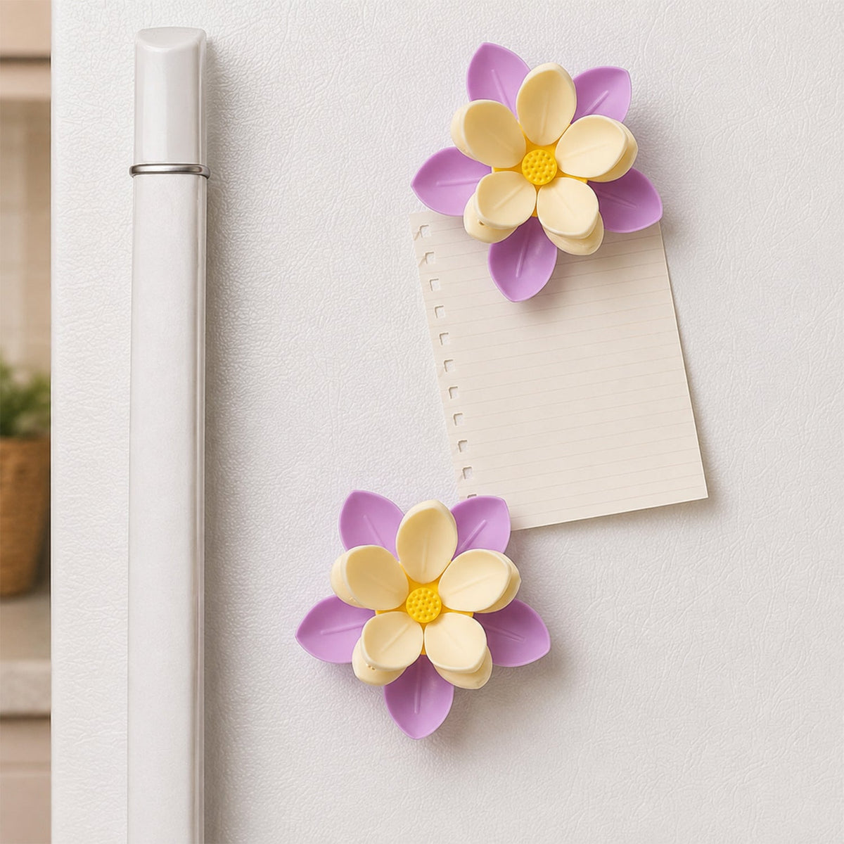 Two purple and yellow flower clips holding a small note to a white refrigerator door.