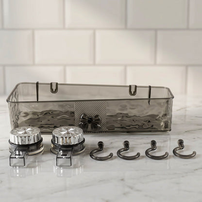 A clear grey plastic caddy, two silver suction cups, and four grey hooks are arranged on a white marble surface.