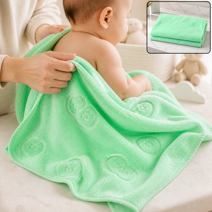 A baby is being dried with a light green microfiber towel featuring embossed heart and flower patterns.